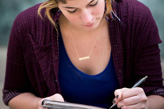 Close-up photo of a student writing in a notebook in the library