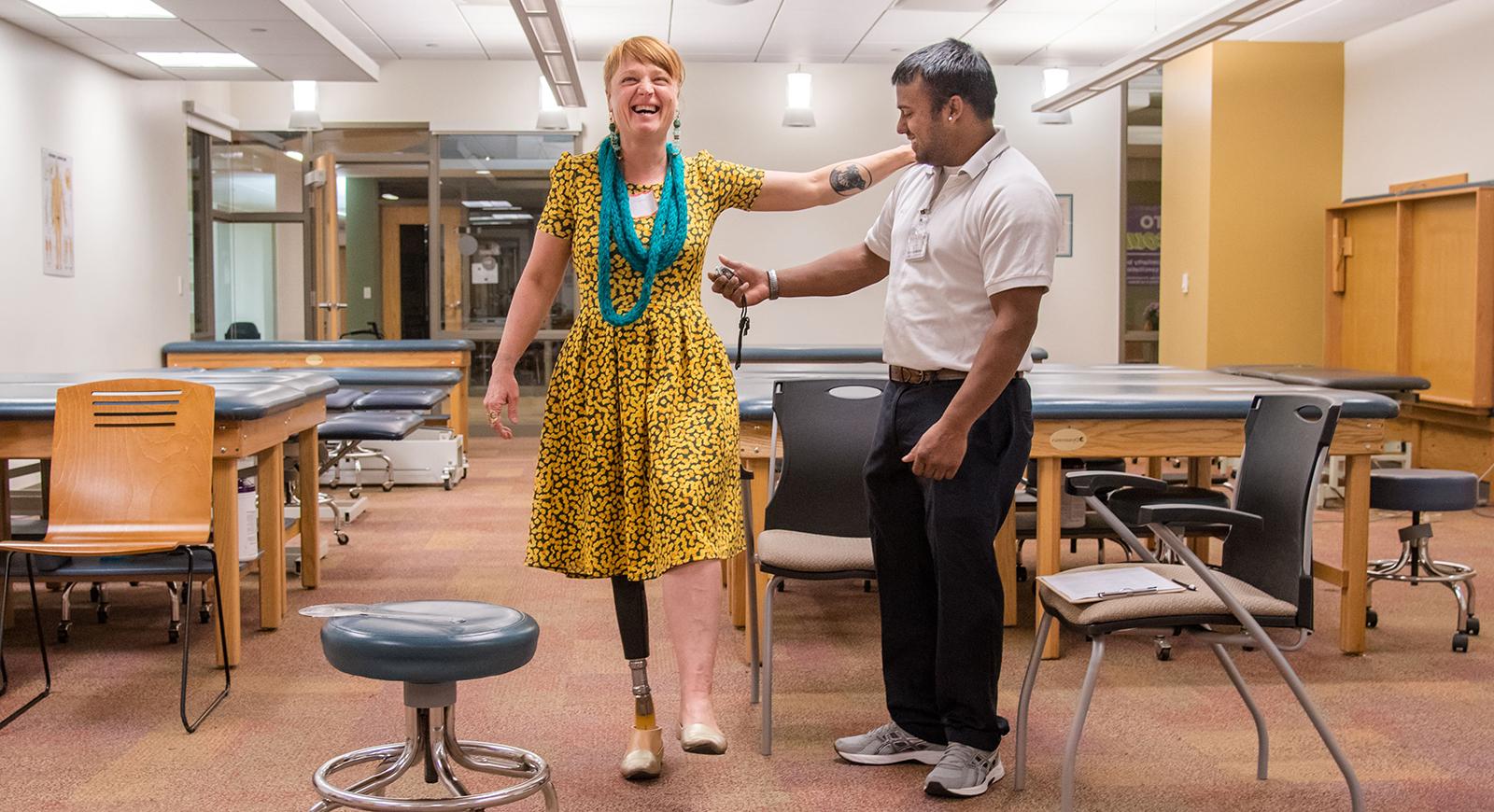 Photo of a physical therapy student helping a woman with a prosthetic leg