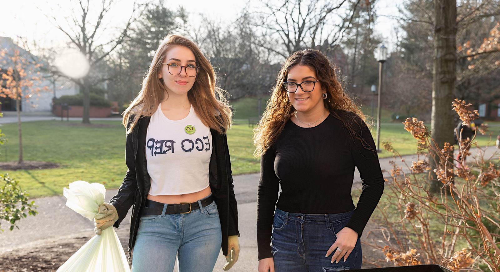 Photo of two Chatham University students, one wearing an Eco Reps shirt, collecting trash on Shadyside Campus